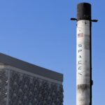 A SpaceX Falcon 9 rocket displayed outdoors against a clear blue sky in Dubai.