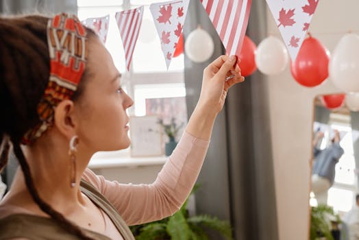 A woman arranging Canada Day banners and balloons for a festive party atmosphere.