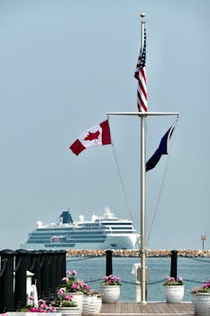 View of a cruise ship approaching Mackinac Island pier with American, Canadian, and local flags flying.